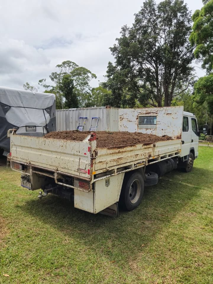 The Ugly Duckling — Mitsubishi Canter 4-tonne tipper on a job, bed loaded with dirt, paint chipped from honest work.